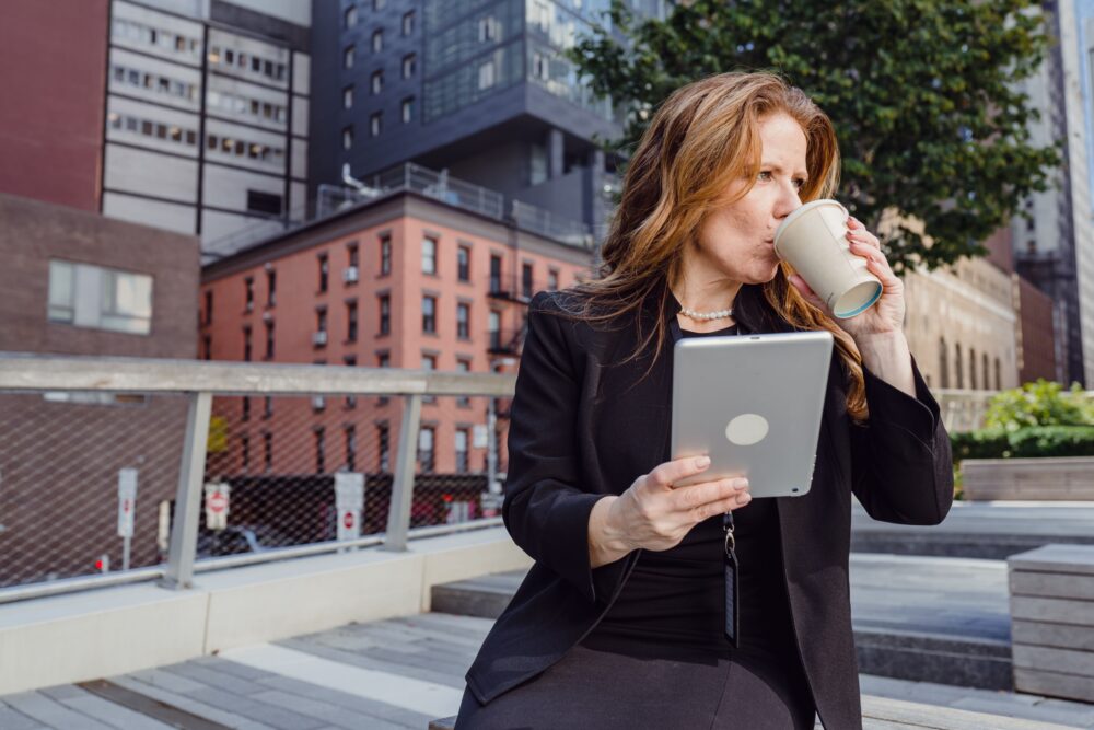 Woman Holding a Cup of Coffee and a Tablet